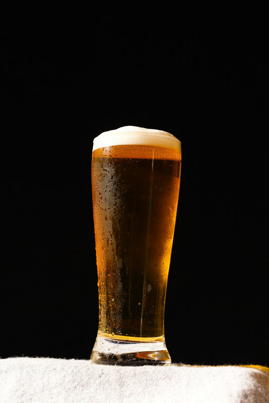 Hazy golden hefeweizen wheat beer in a tall glass with thick white foam head